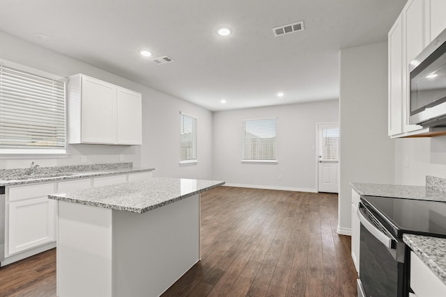 kitchen with white cabinetry, dark wood-type flooring, a kitchen island, and electric range