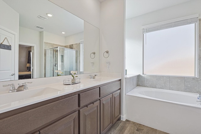 bathroom with wood-type flooring, vanity, and plus walk in shower