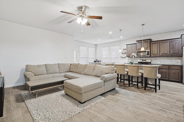 living room with light hardwood / wood-style flooring and ceiling fan