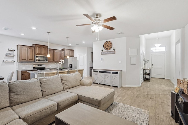 living room featuring sink, ceiling fan, and light wood-type flooring