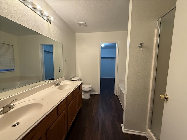 full bathroom featuring separate shower and tub, toilet, wood-type flooring, and a textured ceiling