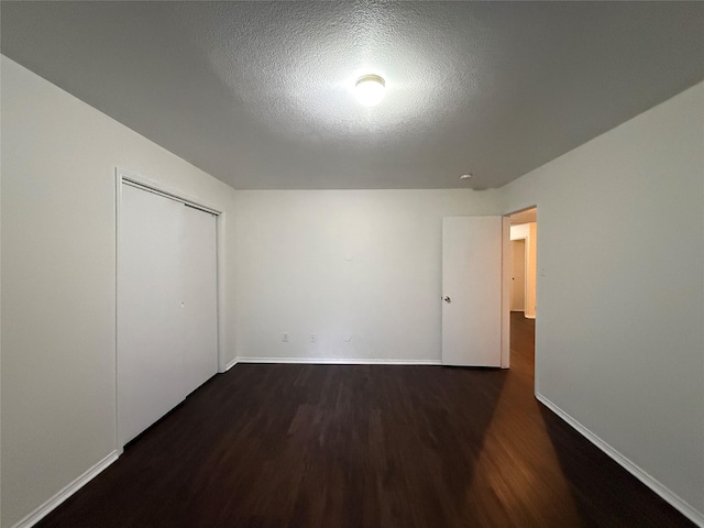 unfurnished bedroom featuring a closet, dark hardwood / wood-style floors, and a textured ceiling