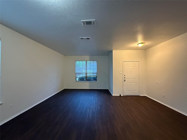 spare room with dark hardwood / wood-style floors and a textured ceiling