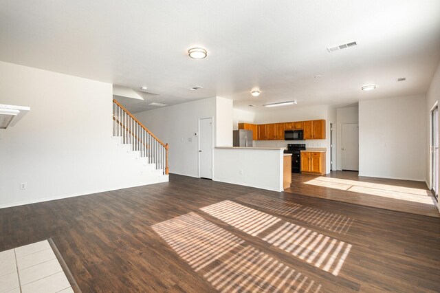 unfurnished living room with wood-type flooring, a textured ceiling, and a tile fireplace