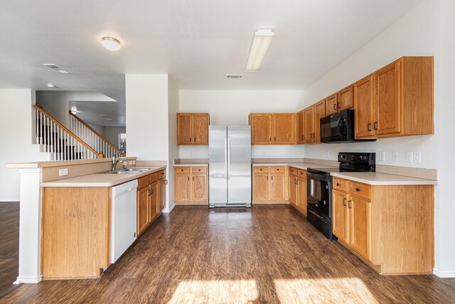 kitchen with kitchen peninsula, sink, dark wood-type flooring, and black appliances