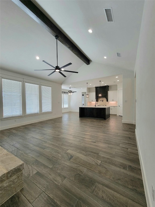 unfurnished living room with dark hardwood / wood-style flooring, lofted ceiling with beams, and ceiling fan