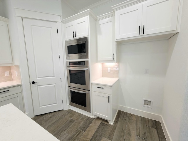 kitchen featuring white cabinets, ornamental molding, stainless steel appliances, and tasteful backsplash