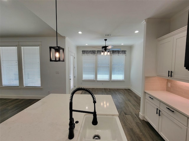 kitchen with backsplash, ceiling fan, sink, pendant lighting, and white cabinets