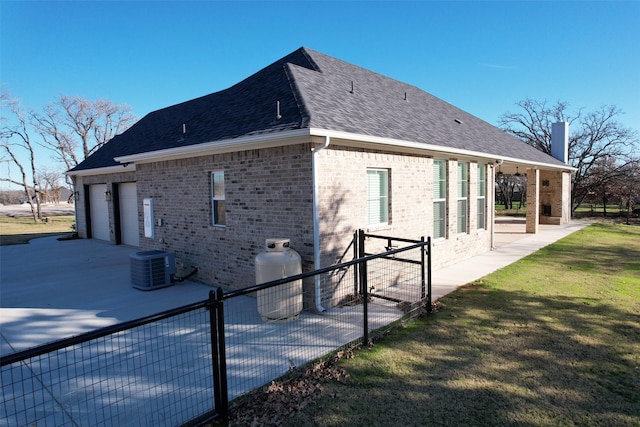 view of side of home with a lawn, a garage, a patio area, and central air condition unit