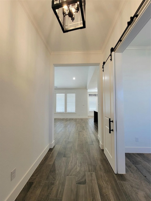 hall with ornamental molding, a barn door, and a notable chandelier