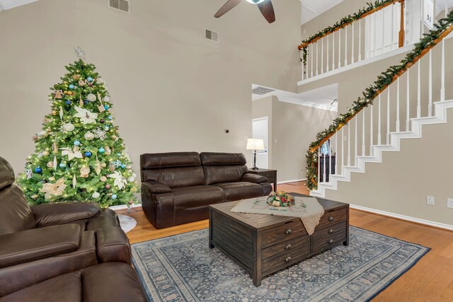 living room featuring ceiling fan, a towering ceiling, and wood-type flooring