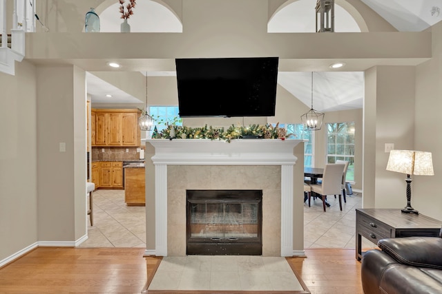 living room featuring a tile fireplace, light hardwood / wood-style floors, and vaulted ceiling