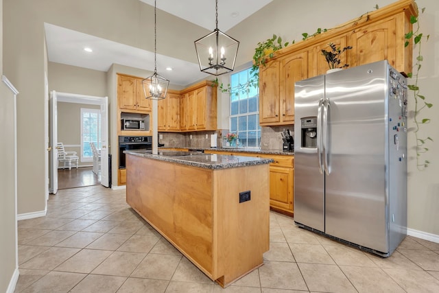 kitchen with appliances with stainless steel finishes, backsplash, pendant lighting, dark stone countertops, and a center island