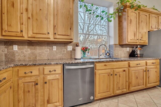 kitchen with stainless steel dishwasher, stone countertops, a healthy amount of sunlight, and sink