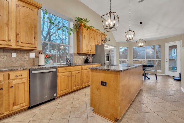 kitchen with light stone countertops, sink, a center island, vaulted ceiling, and appliances with stainless steel finishes