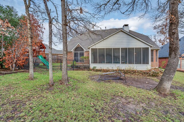 back of house with a playground, a lawn, and a sunroom