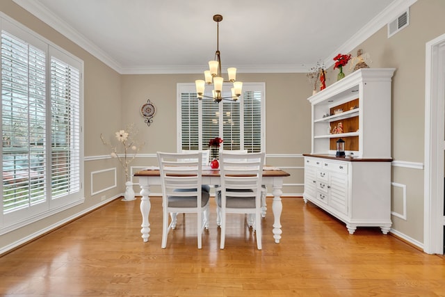 dining area featuring light hardwood / wood-style flooring, a chandelier, and ornamental molding