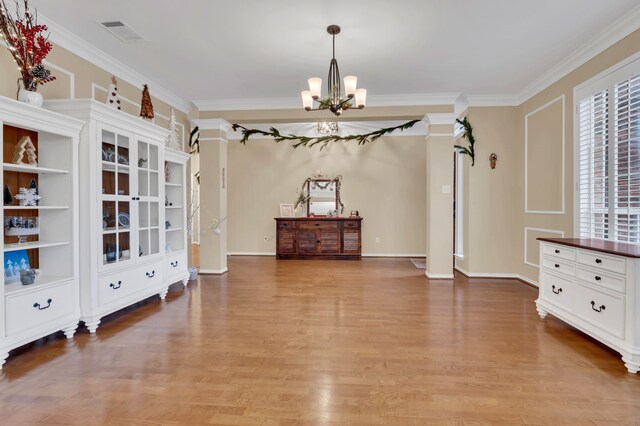 interior space featuring built in features, light hardwood / wood-style flooring, a notable chandelier, and ornamental molding