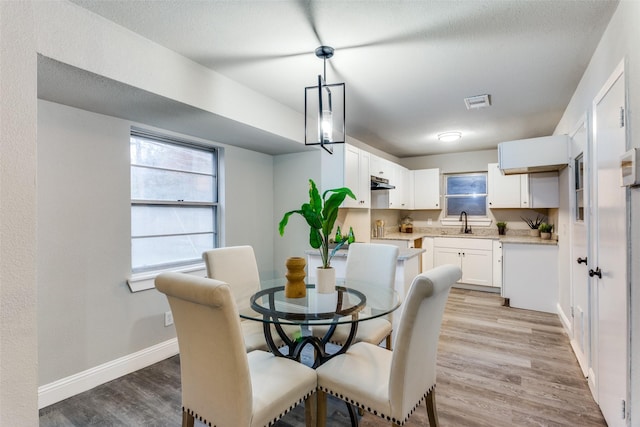 dining space with a healthy amount of sunlight, sink, and light hardwood / wood-style flooring