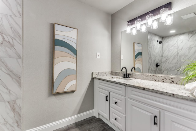 bathroom with hardwood / wood-style floors, vanity, and a tile shower