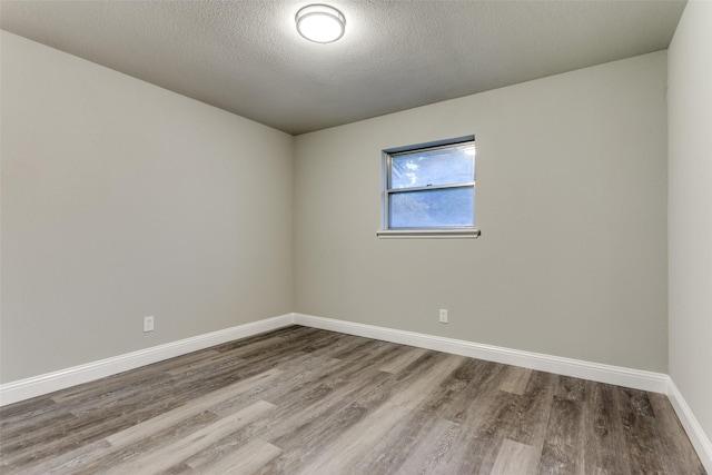 unfurnished room with wood-type flooring and a textured ceiling