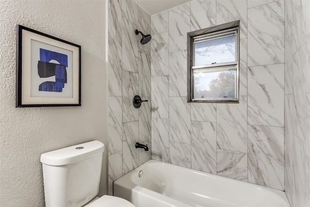 bathroom featuring tiled shower / bath combo and toilet