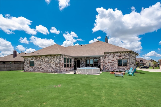 back of house featuring a fenced in pool and a lawn