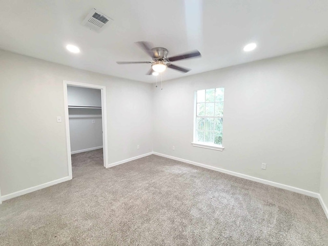 unfurnished bedroom with carpet flooring, a walk in closet, a closet, and ceiling fan