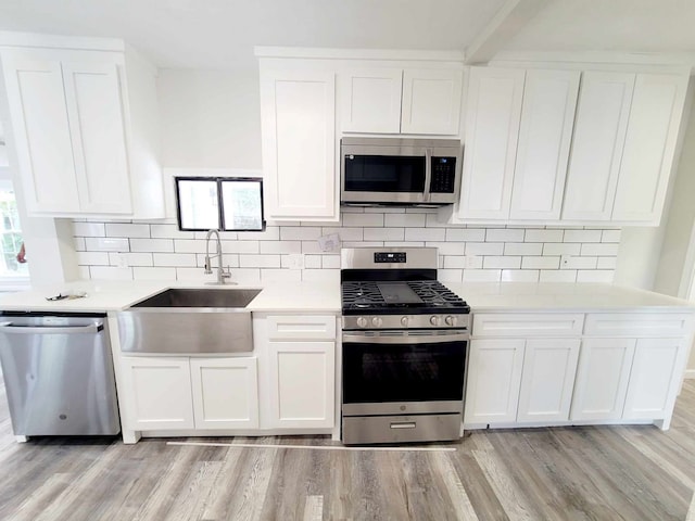 kitchen with sink, white cabinets, light wood-type flooring, and appliances with stainless steel finishes