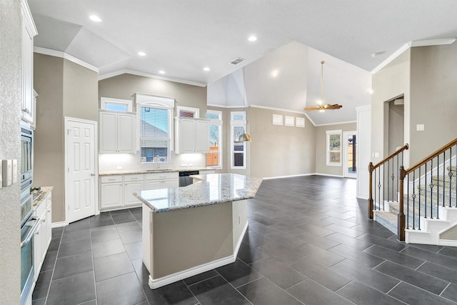 kitchen with light stone countertops, stainless steel appliances, a center island, and white cabinets