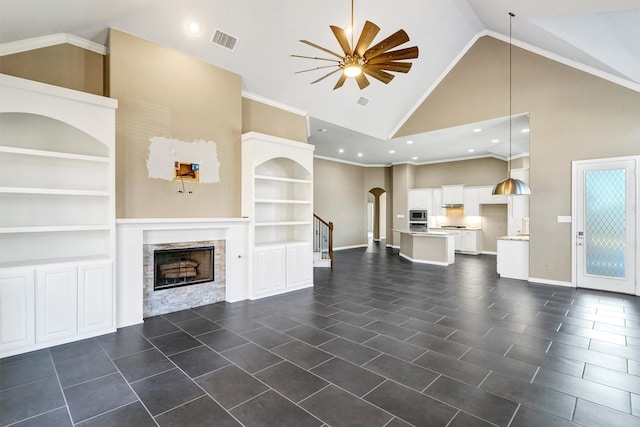 unfurnished living room with high vaulted ceiling, crown molding, built in features, and ceiling fan