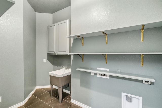 clothes washing area featuring cabinets, hookup for a washing machine, dark tile patterned floors, and electric dryer hookup