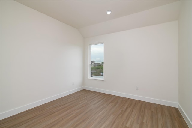 empty room featuring hardwood / wood-style flooring and vaulted ceiling