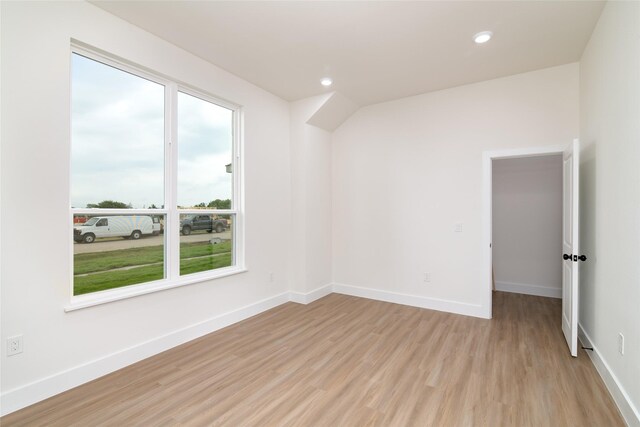 empty room with baseboards, a healthy amount of sunlight, and light wood finished floors
