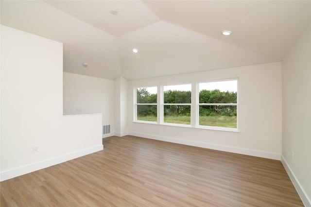 empty room with light wood-type flooring, vaulted ceiling, baseboards, visible vents, and recessed lighting