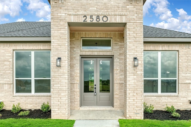 entrance to property with french doors and a shingled roof