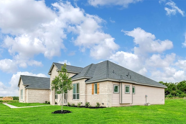 back of property featuring a lawn, brick siding, and roof with shingles