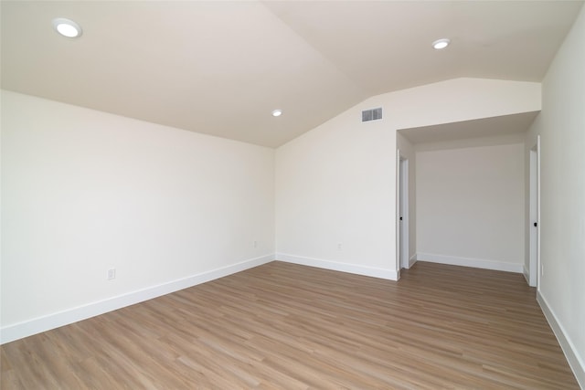 spare room with vaulted ceiling and light hardwood / wood-style flooring