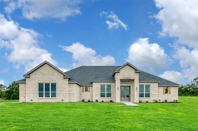 view of front of house featuring a front lawn, brick siding, roof with shingles, and french doors