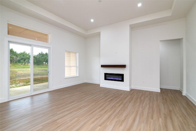 unfurnished living room featuring baseboards, a glass covered fireplace, light wood-style floors, and recessed lighting