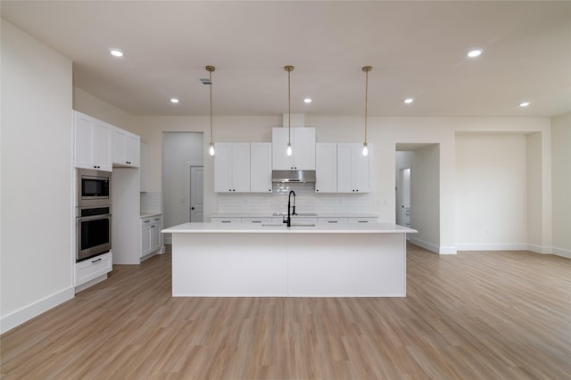 kitchen with under cabinet range hood, stainless steel appliances, light countertops, baseboards, and tasteful backsplash