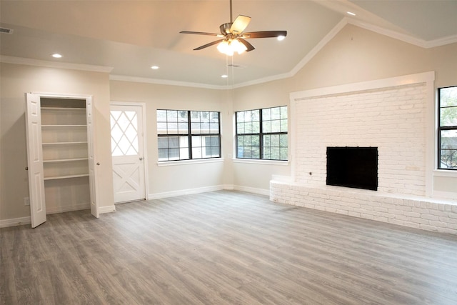 unfurnished living room featuring hardwood / wood-style floors, lofted ceiling, ceiling fan, ornamental molding, and a fireplace