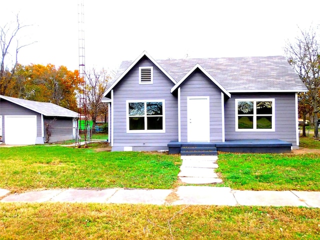 view of front of house featuring a garage, an outbuilding, and a front yard