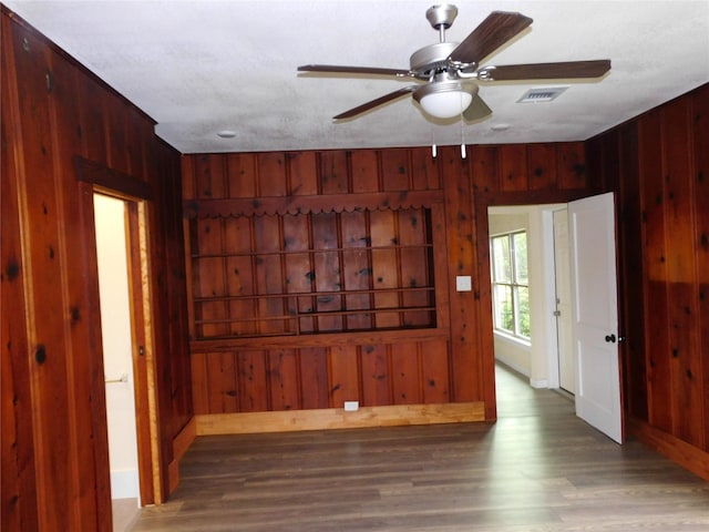 empty room featuring hardwood / wood-style flooring, ceiling fan, and wooden walls