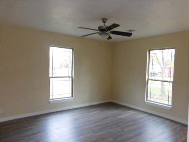 spare room with dark hardwood / wood-style flooring, a wealth of natural light, and ceiling fan