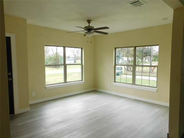 empty room with ceiling fan, light hardwood / wood-style floors, and a healthy amount of sunlight