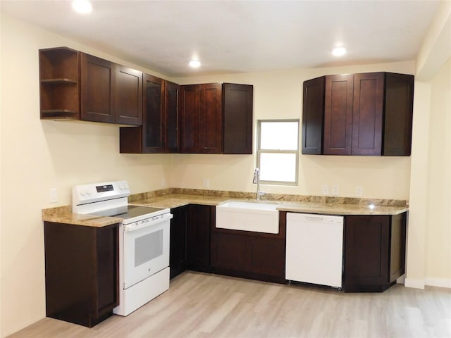 kitchen featuring dark brown cabinetry, sink, light hardwood / wood-style floors, and white appliances