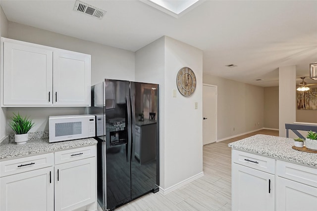 kitchen featuring white cabinetry, black refrigerator with ice dispenser, light stone counters, and light hardwood / wood-style flooring