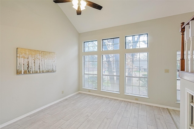 empty room with ceiling fan, a healthy amount of sunlight, high vaulted ceiling, and light wood-type flooring