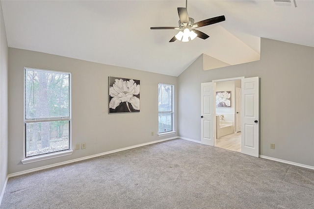 unfurnished bedroom featuring ceiling fan, ensuite bath, lofted ceiling, and light carpet